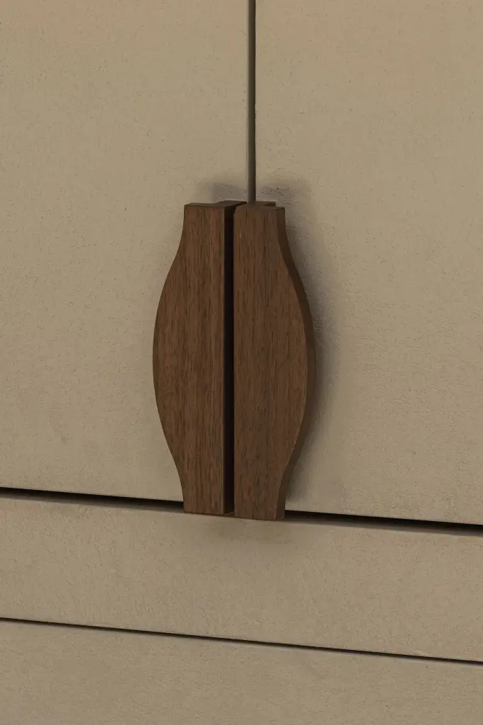 Detail van een gebogen walnoten handgreep op een crème kastdeur, Herenhuis in Brugge, interieur Laura Calleeuw