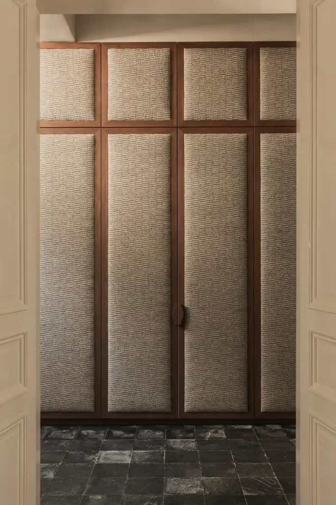 Inkomhal met garderobekast met gestoffeerde panelen in walnoten kader en leistenen vloer, Herenhuis in Brugge, interieur Laura Calleeuw