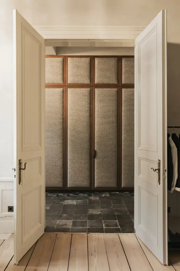 Inkomhal met garderobekast met gestoffeerde panelen in walnoten kader en leistenen vloer, Herenhuis in Brugge, interieur Laura Calleeuw