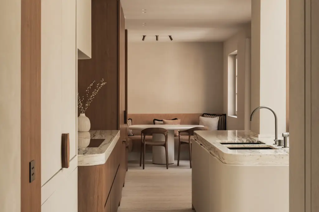 Keuken met afgerond eiland in onyx, walnoten kasten en eethoek op de achtergrond, Herenhuis in Brugge, interieur Laura Calleeuw