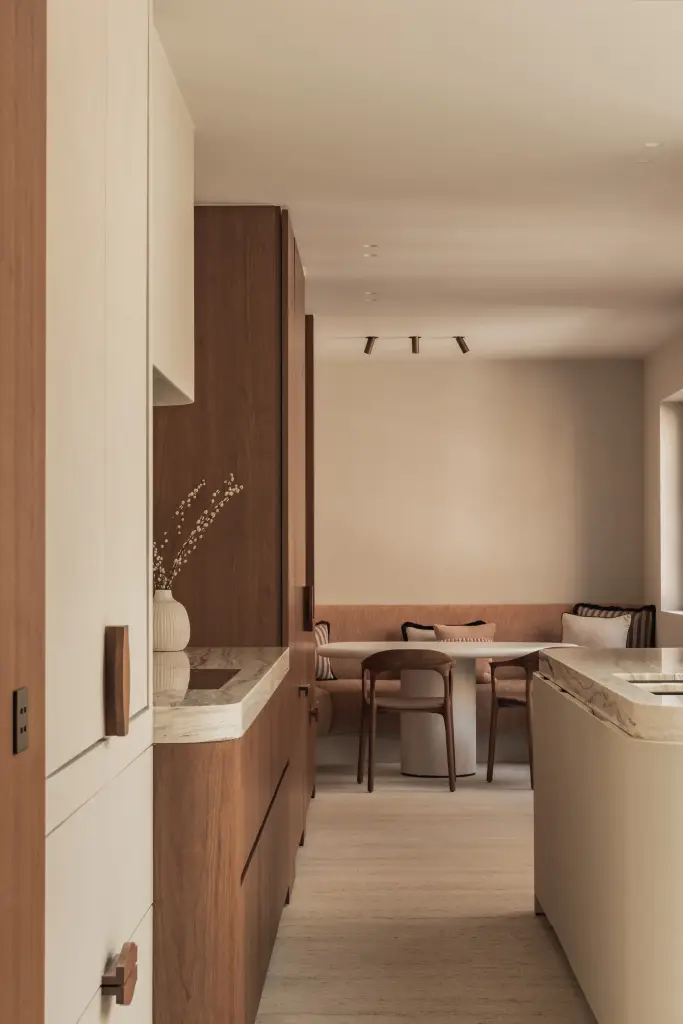 Keuken met afgerond eiland in onyx, walnoten kasten en eethoek op de achtergrond, Herenhuis in Brugge, interieur Laura Calleeuw