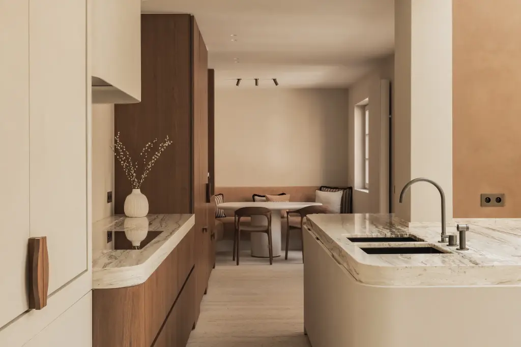 Keuken met afgerond eiland in onyx, walnoten kasten en eethoek op de achtergrond, Herenhuis in Brugge, interieur Laura Calleeuw