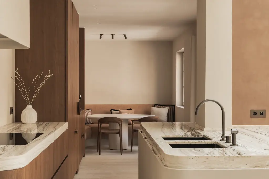 Keuken met afgerond eiland in onyx, walnoten kasten en eethoek op de achtergrond, Herenhuis in Brugge, interieur Laura Calleeuw