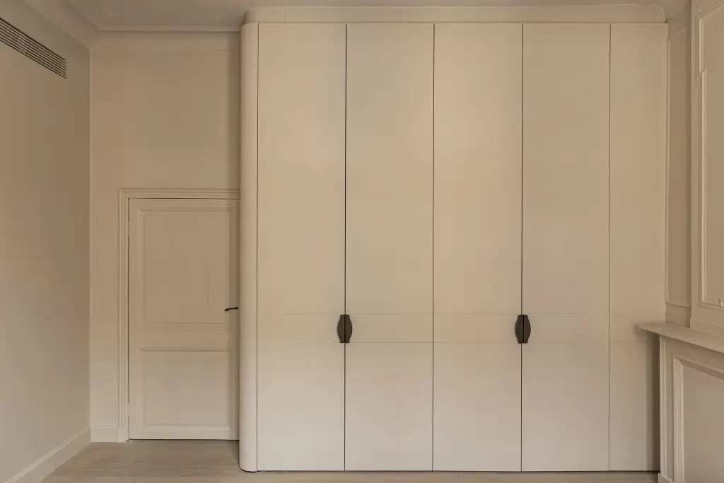 Kleerkasten in crème met gebogen hoek en bronzen handgrepen, Herenhuis in Brugge, interieur Laura Calleeuw