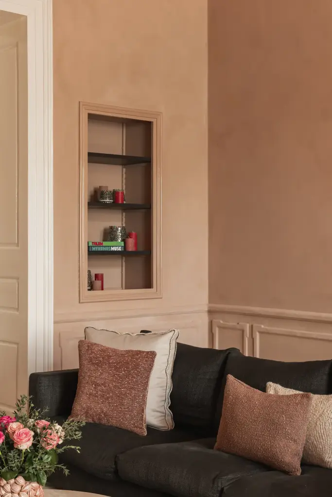 Salon met antracieten hoekzetel, marmeren schouw en kroonluchter in roze kalkverf, Herenhuis in Brugge, interieur Laura Calleeuw