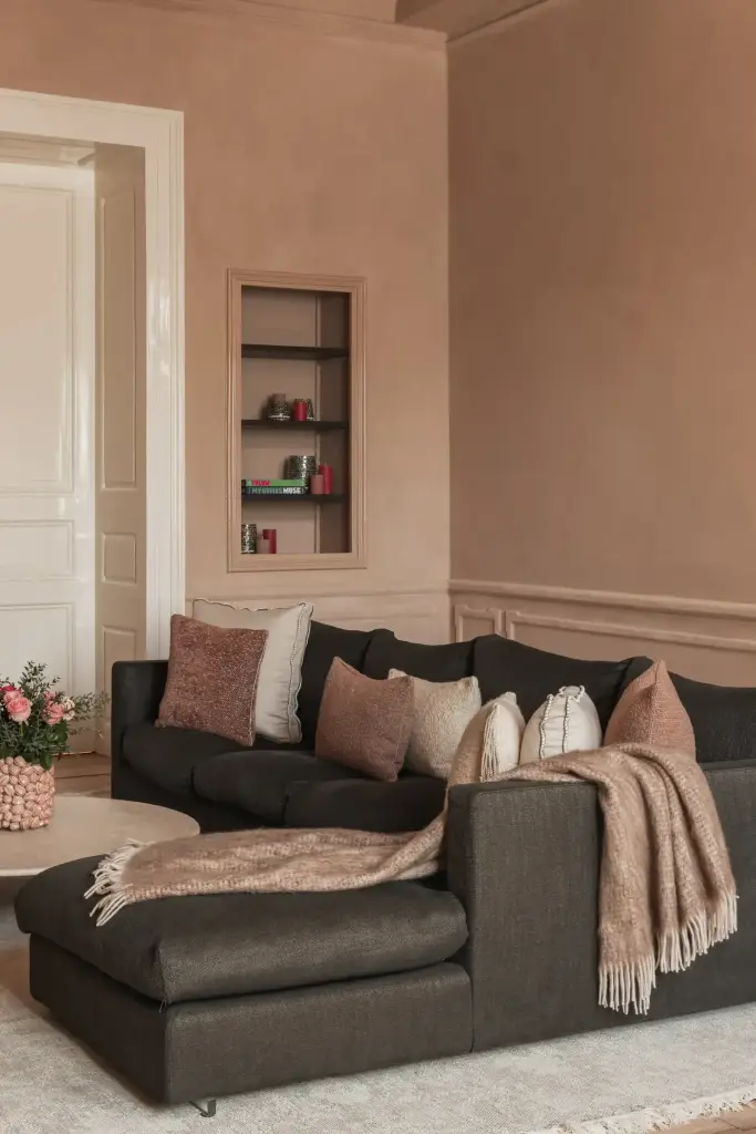 Salon met antracieten hoekzetel, marmeren schouw en kroonluchter in roze kalkverf, Herenhuis in Brugge, interieur Laura Calleeuw