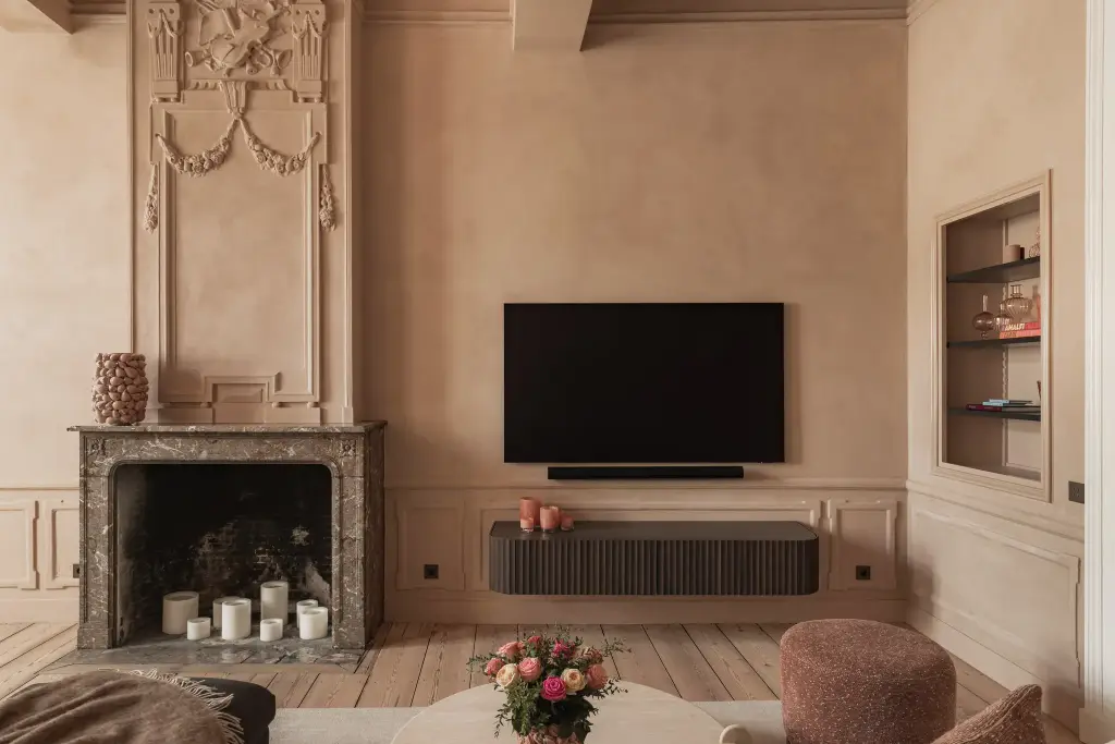 Salon met televisie, marmeren schouw, stucwerk ornament en lamellenmeubel, Herenhuis in Brugge, interieur Laura Calleeuw