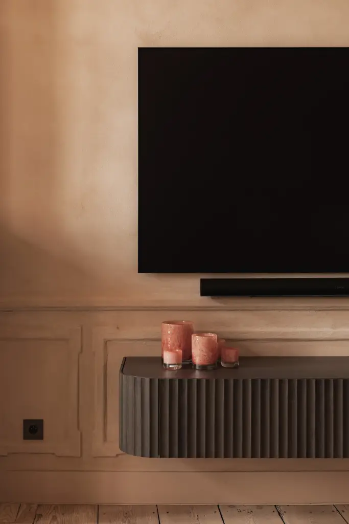 Salon met televisie, marmeren schouw, stucwerk ornament en lamellenmeubel, Herenhuis in Brugge, interieur Laura Calleeuw