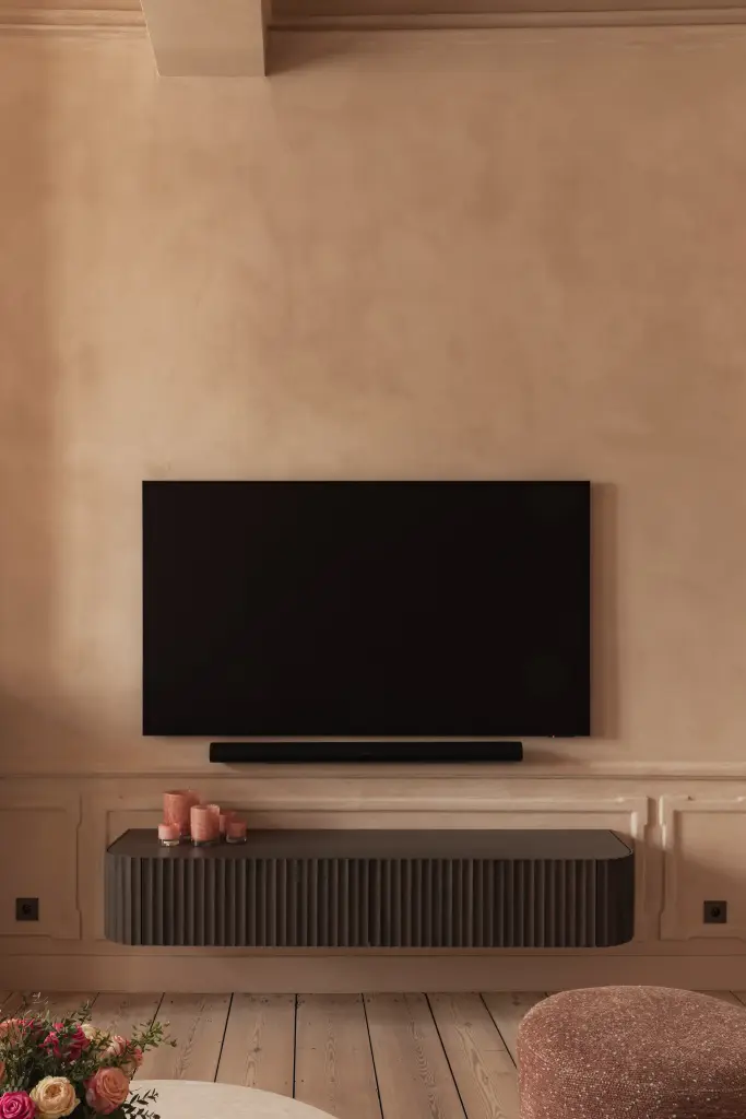 Salon met televisie, marmeren schouw, stucwerk ornament en lamellenmeubel, Herenhuis in Brugge, interieur Laura Calleeuw