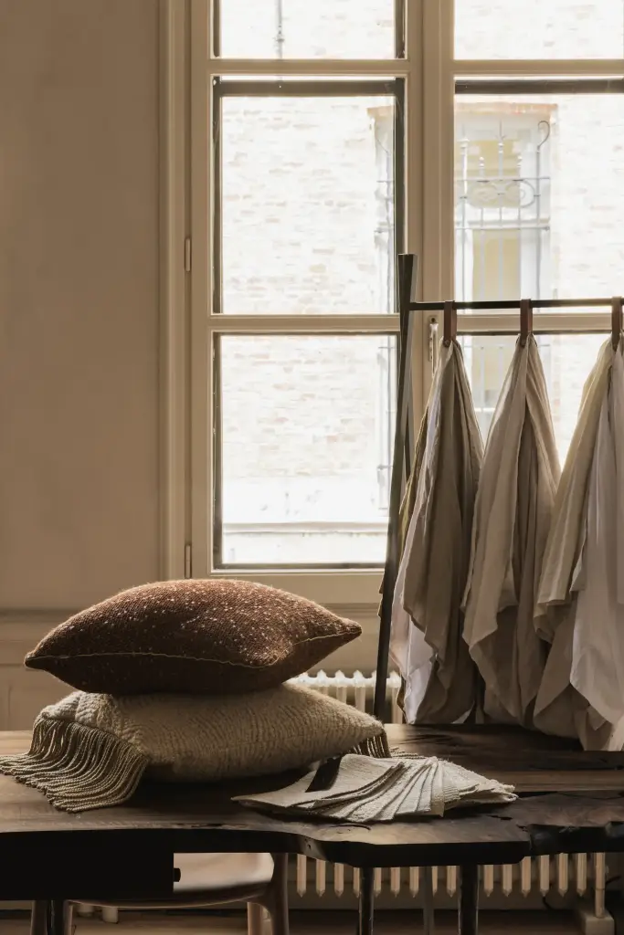 Ruimte met hoge ramen, houten werktafel en stalen op kledingrek, Herenhuis in Brugge, interieur Laura Calleeuw