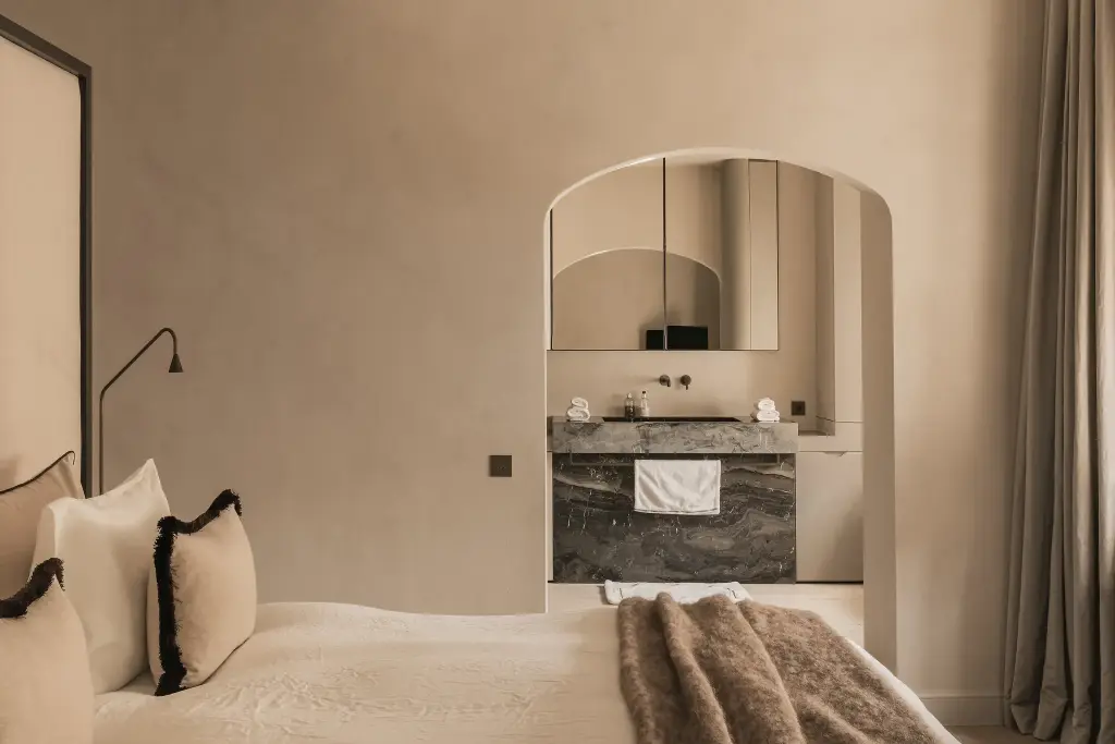 Slaapkamer met boogvormige doorgang naar de badkamer met marmeren wastafel, Herenhuis in Brugge, interieur Laura Calleeuw