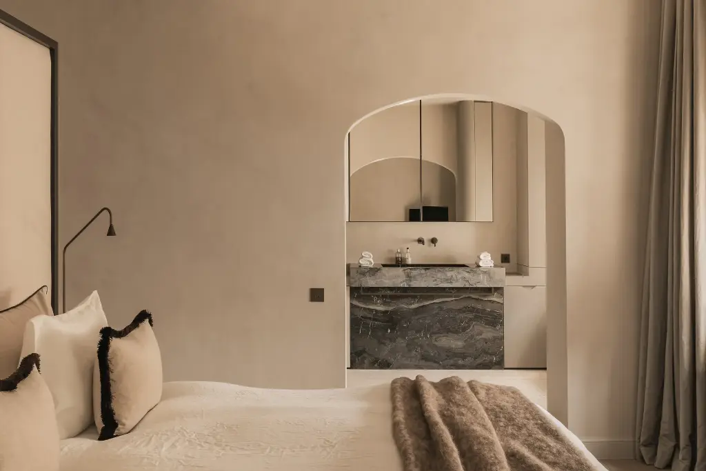 Slaapkamer met boogvormige doorgang naar de badkamer met marmeren wastafel, Herenhuis in Brugge, interieur Laura Calleeuw