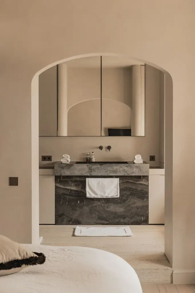 Slaapkamer met boogvormige doorgang naar de badkamer met marmeren wastafel, Herenhuis in Brugge, interieur Laura Calleeuw