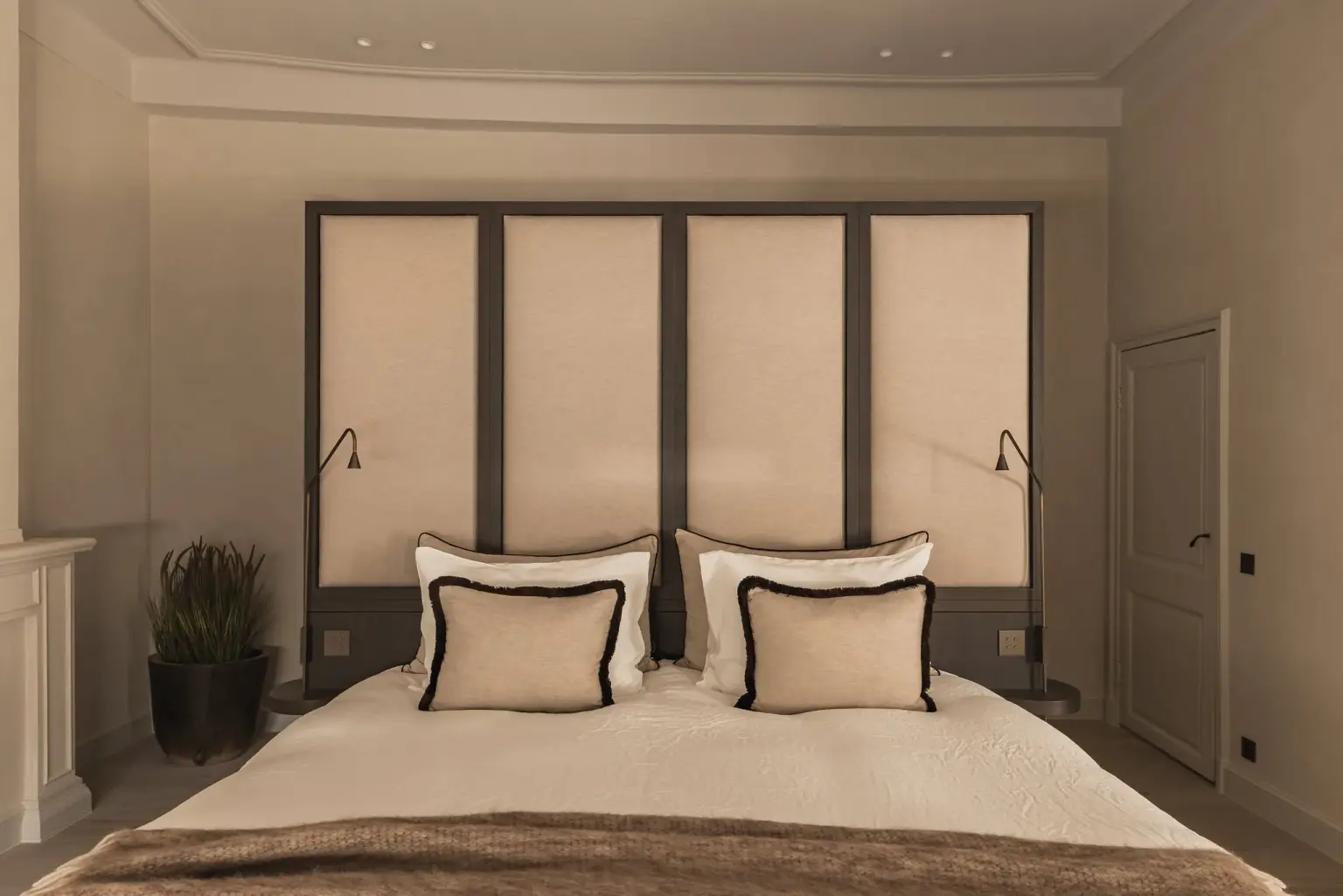 Slaapkamer met gestoffeerd hoofdbord, sierkussens met zwarte rand en leeslamp, Herenhuis in Brugge, interieur Laura Calleeuw
