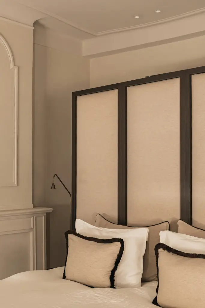 Slaapkamer met gestoffeerd hoofdbord, sierkussens met zwarte rand en leeslamp, Herenhuis in Brugge, interieur Laura Calleeuw