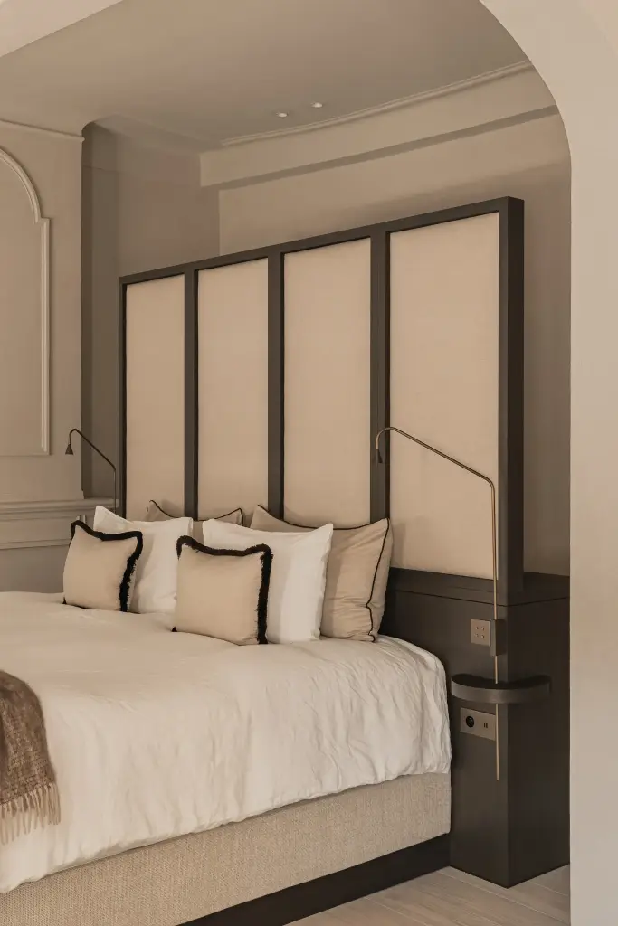 Slaapkamer met gestoffeerd hoofdbord, sierkussens met zwarte rand en leeslamp, Herenhuis in Brugge, interieur Laura Calleeuw