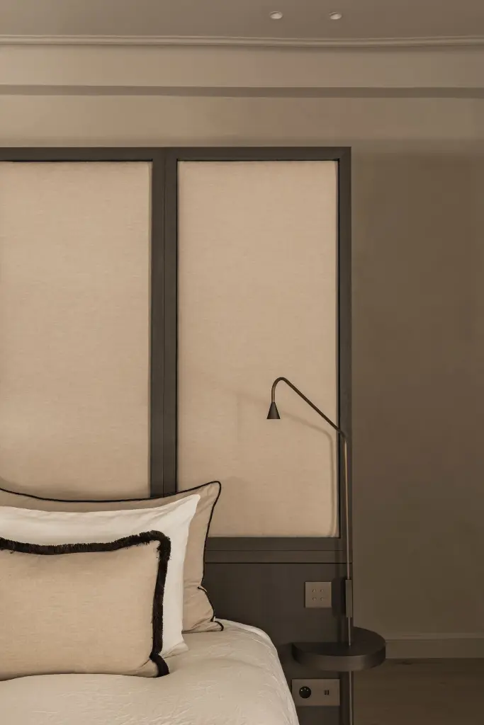 Slaapkamer met gestoffeerd hoofdbord, sierkussens met zwarte rand en leeslamp, Herenhuis in Brugge, interieur Laura Calleeuw