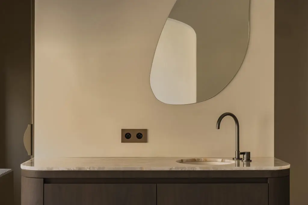 Wastafelmeubel met onyx blad, zwarte kraan en organische spiegel, Herenhuis in Brugge, interieur Laura Calleeuw