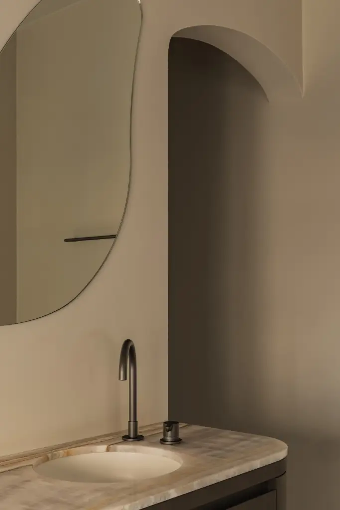 Wastafelmeubel met onyx blad, zwarte kraan en organische spiegel, Herenhuis in Brugge, interieur Laura Calleeuw