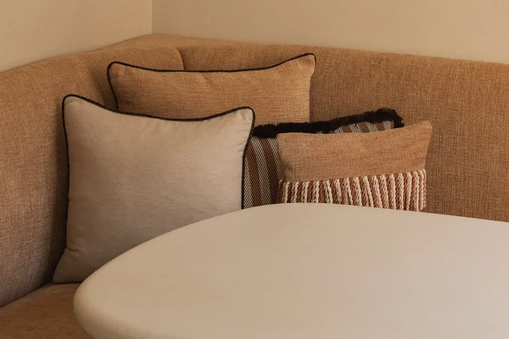 Ronde zitbank in oranje stof met sierkussens en ronde eettafel, Herenhuis in Brugge, interieur Laura Calleeuw