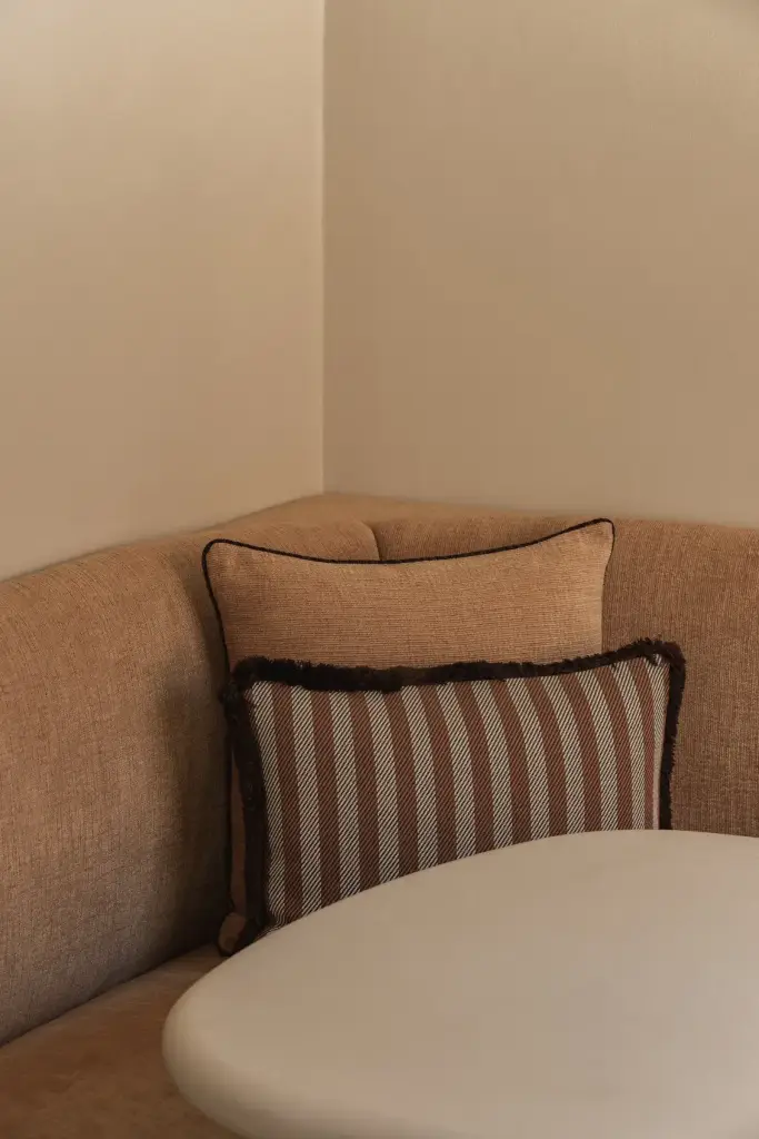 Ronde zitbank in oranje stof met sierkussens en ronde eettafel, Herenhuis in Brugge, interieur Laura Calleeuw
