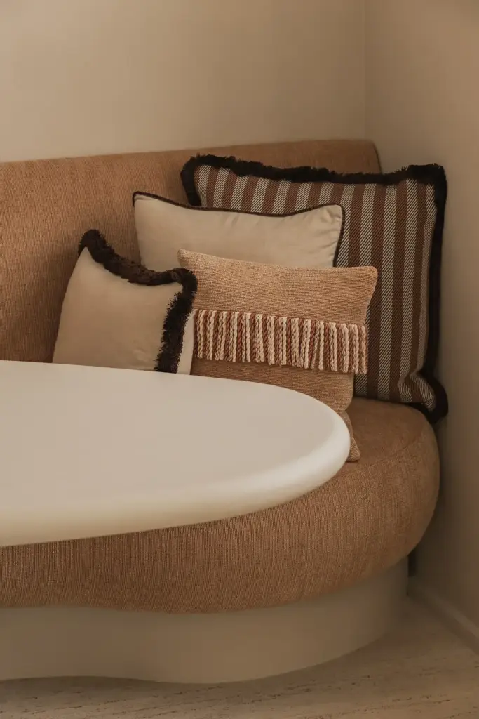 Ronde zitbank in oranje stof met sierkussens en ronde eettafel, Herenhuis in Brugge, interieur Laura Calleeuw