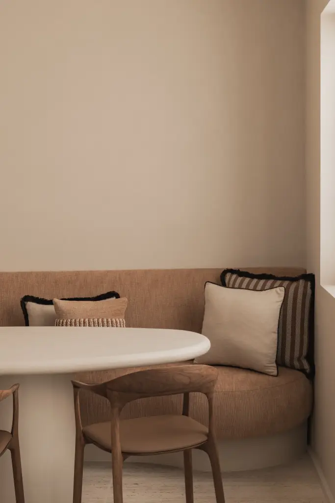 Ronde zitbank in oranje stof met sierkussens en ronde eettafel, Herenhuis in Brugge, interieur Laura Calleeuw