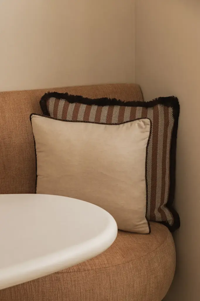 Ronde zitbank in oranje stof met sierkussens en ronde eettafel, Herenhuis in Brugge, interieur Laura Calleeuw