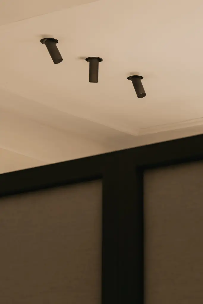 Zwarte inbouwspots in het plafond boven het hoofdbord, Herenhuis in Brugge, interieur Laura Calleeuw