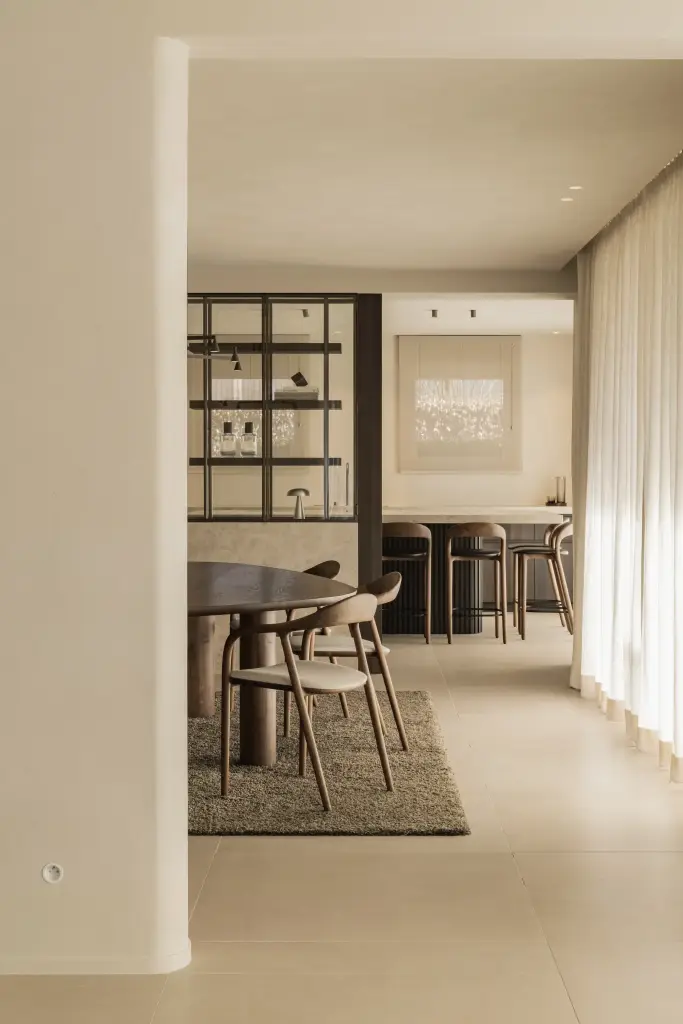 Doorkijk naar de eethoek en leefruimte langs een linnen gordijn, Villa in Loppem, interieur Laura Calleeuw