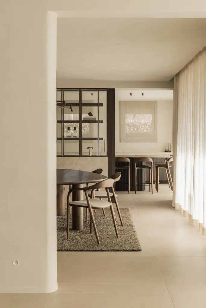 Doorkijk naar de eethoek en leefruimte langs een linnen gordijn, Villa in Loppem, interieur Laura Calleeuw