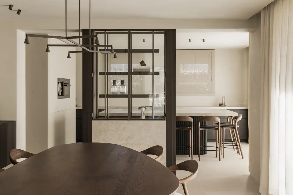 Eethoek en stalen vitrinekast met op de achtergrond het keukeneiland met barkrukken, Villa in Loppem, interieur Laura Calleeuw