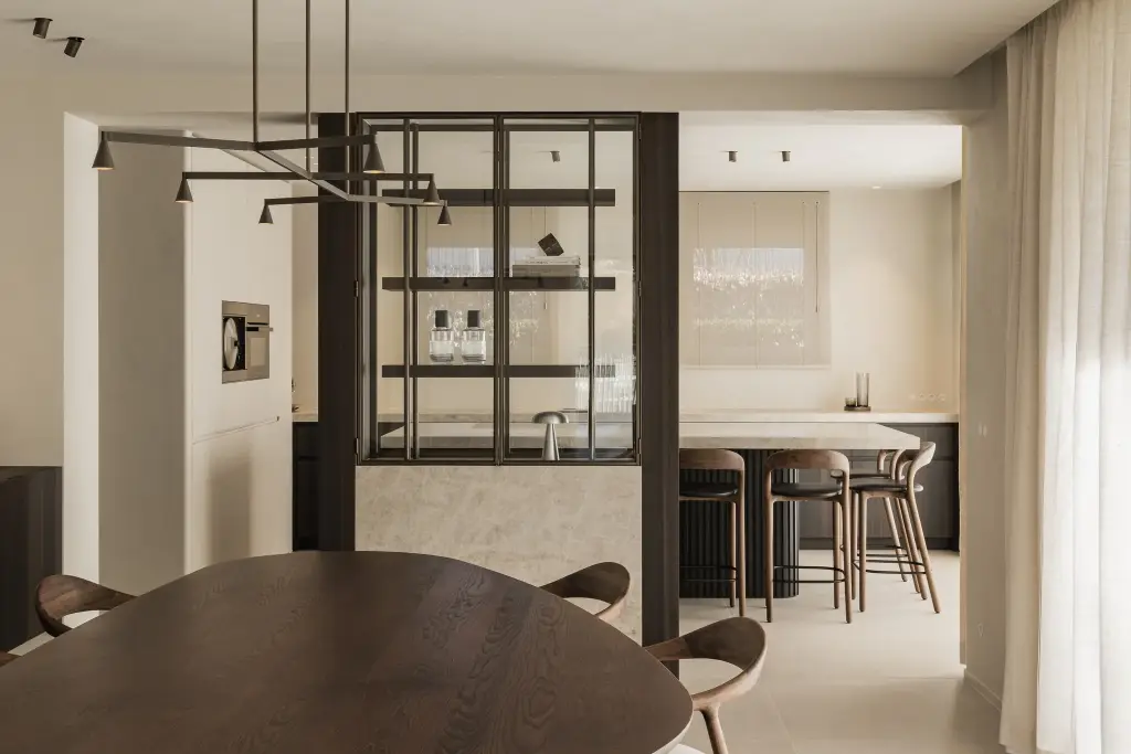 Eethoek en stalen vitrinekast met op de achtergrond het keukeneiland met barkrukken, Villa in Loppem, interieur Laura Calleeuw