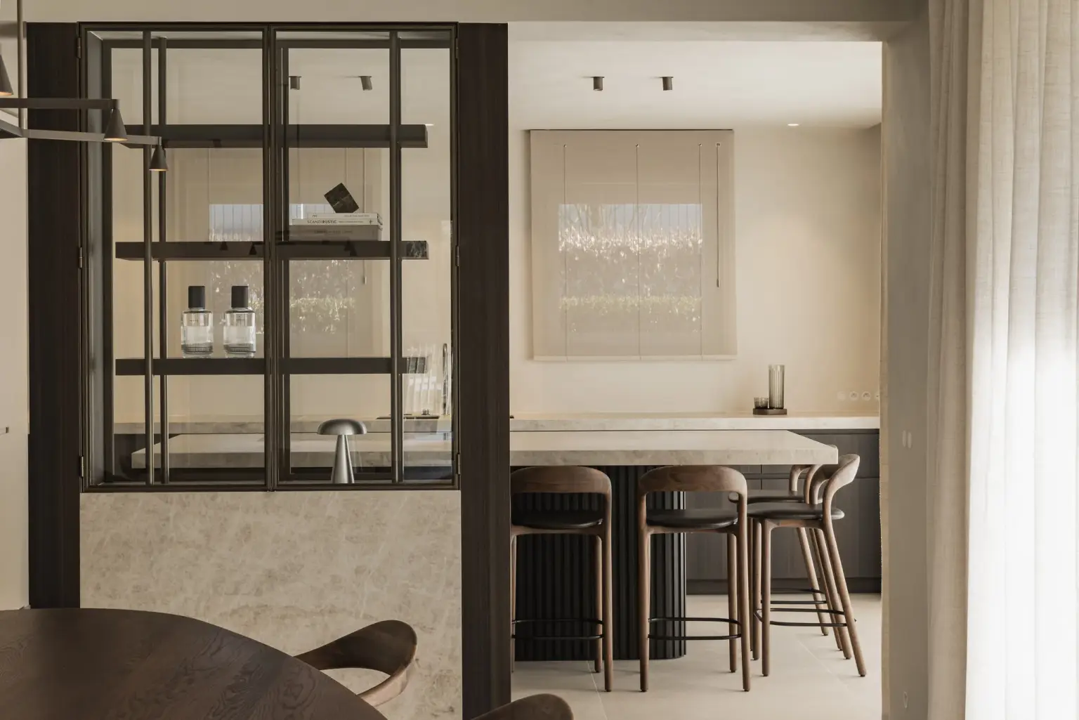 Eethoek en stalen vitrinekast met op de achtergrond het keukeneiland met barkrukken, Villa in Loppem, interieur Laura Calleeuw