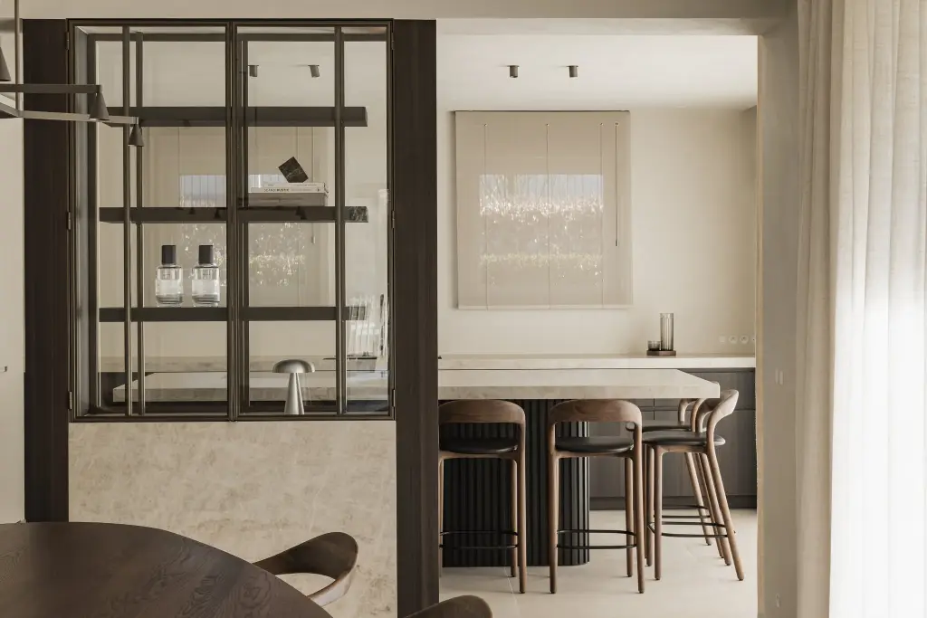 Eethoek en stalen vitrinekast met op de achtergrond het keukeneiland met barkrukken, Villa in Loppem, interieur Laura Calleeuw