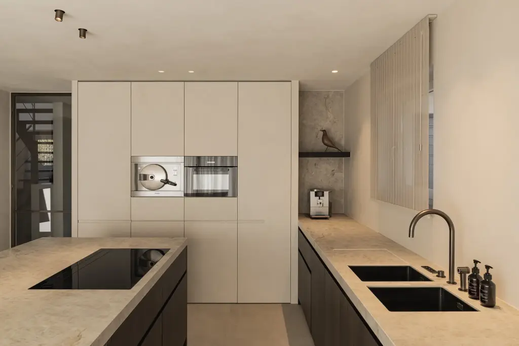 Keuken met kookeiland, dubbele spoelbak en hoge kastenwand met ovens, Villa in Loppem, interieur Laura Calleeuw