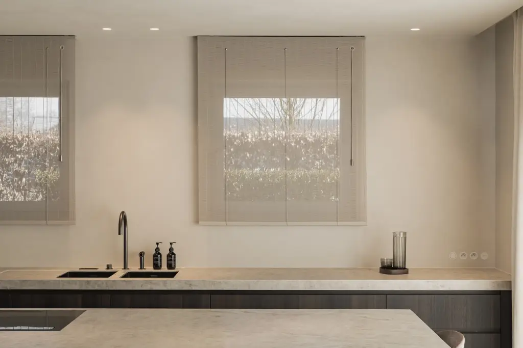 Keukenwerkblad met dubbele spoelbak voor het raam met rolgordijn, Villa in Loppem, interieur Laura Calleeuw