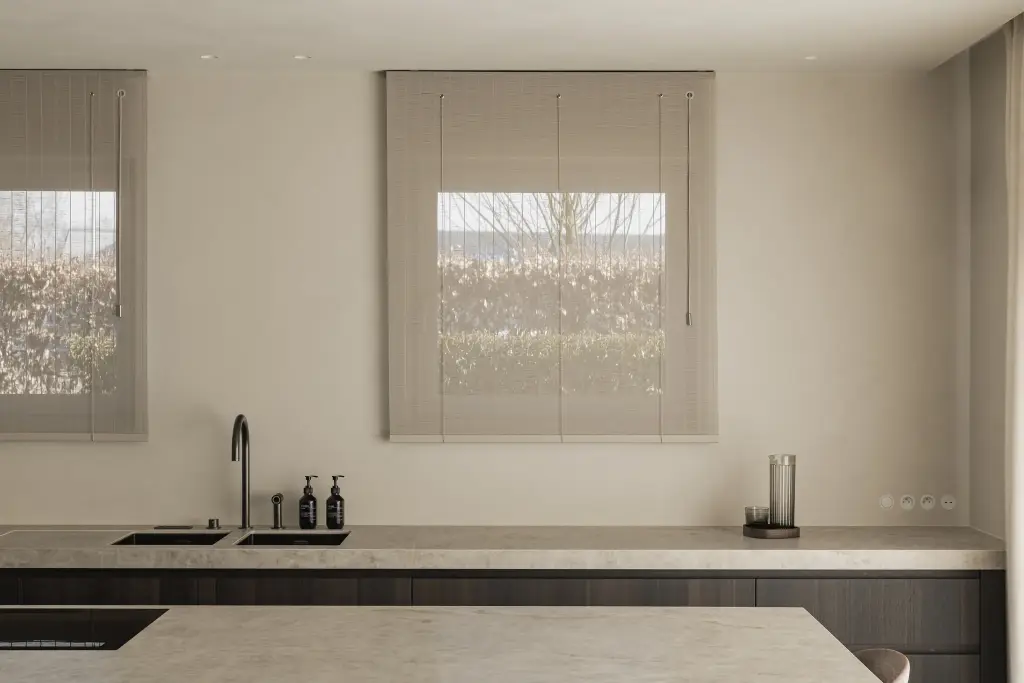 Keukenwerkblad met dubbele spoelbak voor het raam met rolgordijn, Villa in Loppem, interieur Laura Calleeuw