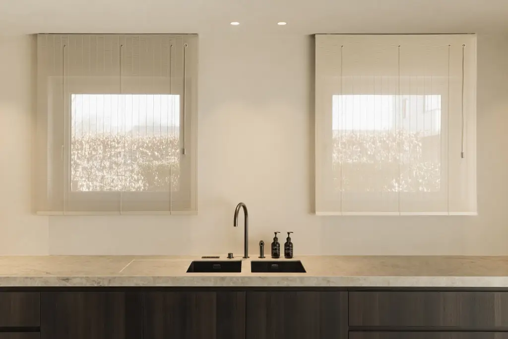 Keuken met twee ramen met rolgordijnen en spoelbak, Villa in Loppem, interieur Laura Calleeuw