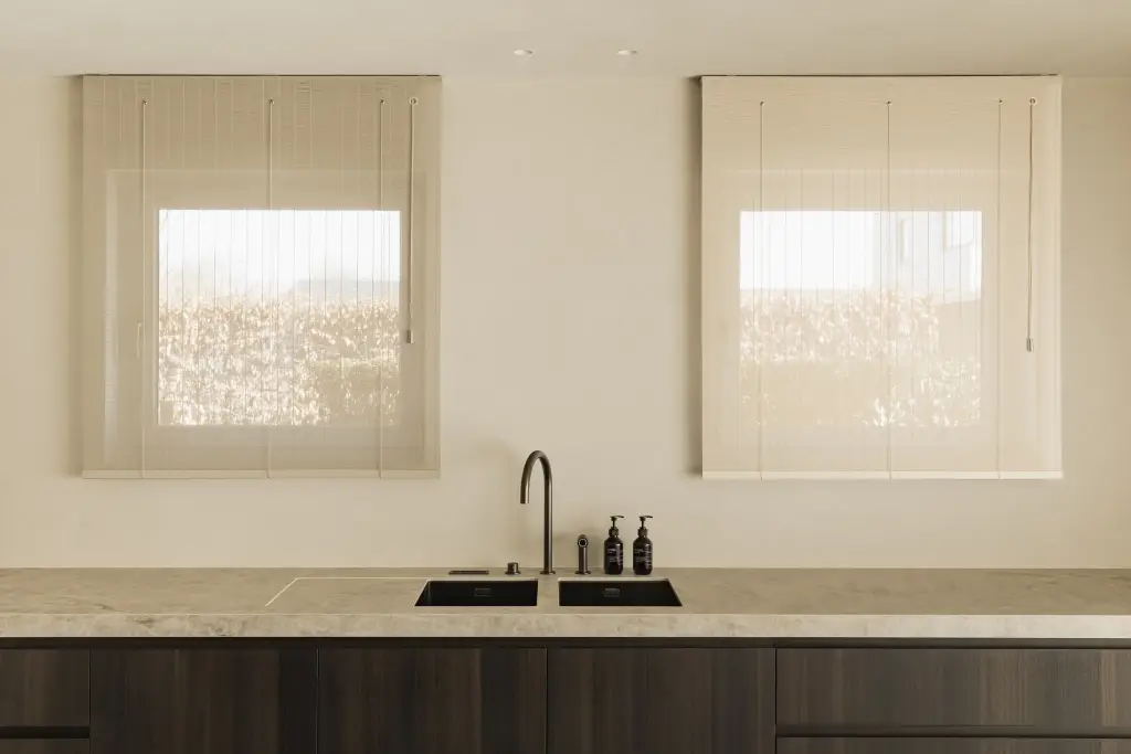 Keuken met twee ramen met rolgordijnen en spoelbak, Villa in Loppem, interieur Laura Calleeuw