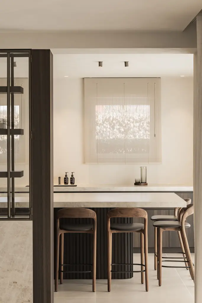 Keukeneiland met barkrukken en een raam met geplooid rolgordijn, Villa in Loppem, interieur Laura Calleeuw