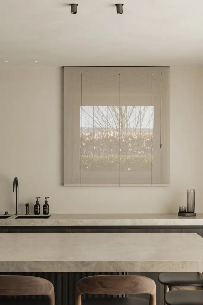 Keukeneiland met barkrukken voor het raam met rolgordijn, Villa in Loppem, interieur Laura Calleeuw