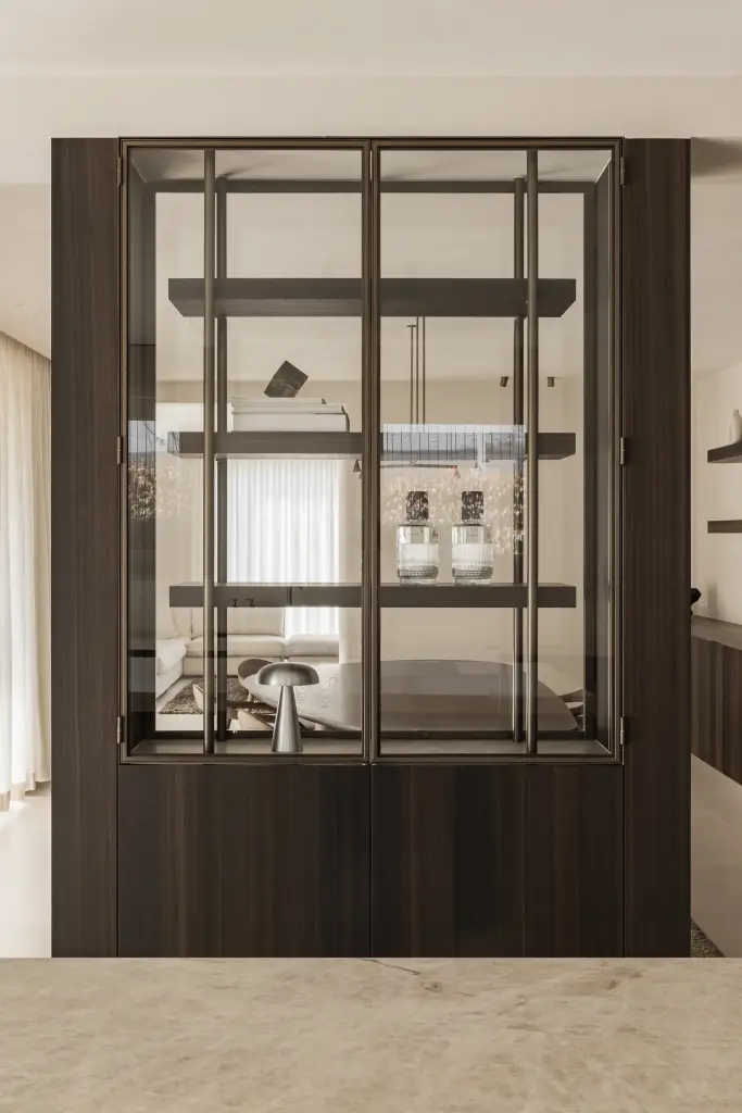 Stalen vitrinekast met parfumflesjes en paddenstoellamp met doorkijk naar de leefruimte, Villa in Loppem, interieur Laura Calleeuw