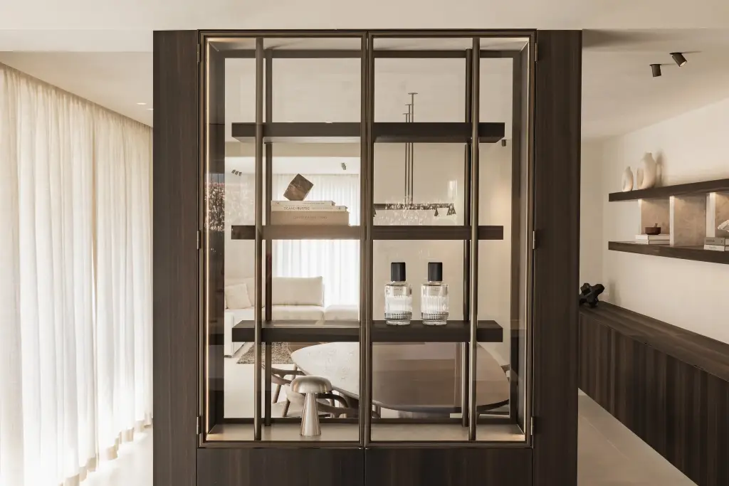 Stalen vitrinekast met parfumflesjes en paddenstoellamp met doorkijk naar de leefruimte, Villa in Loppem, interieur Laura Calleeuw