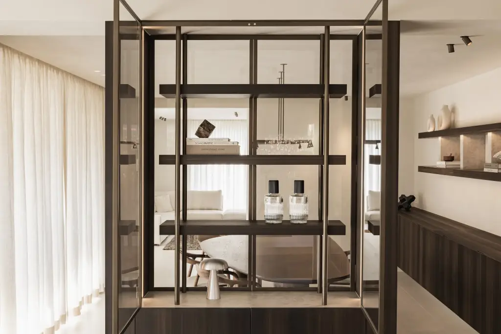 Stalen vitrinekast met parfumflesjes en paddenstoellamp met doorkijk naar de leefruimte, Villa in Loppem, interieur Laura Calleeuw