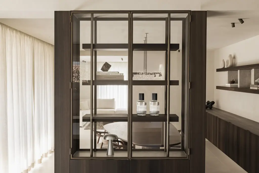 Stalen vitrinekast met parfumflesjes en paddenstoellamp met doorkijk naar de leefruimte, Villa in Loppem, interieur Laura Calleeuw