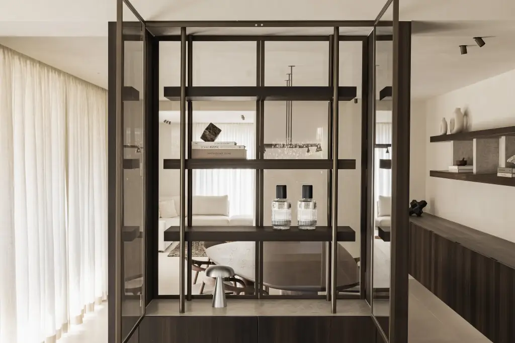 Stalen vitrinekast met parfumflesjes en paddenstoellamp met doorkijk naar de leefruimte, Villa in Loppem, interieur Laura Calleeuw