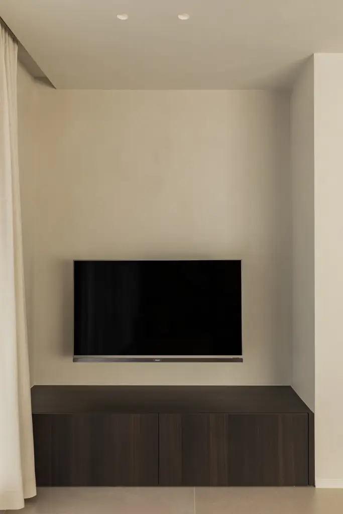 Televisienis in microcement boven een donker houten meubel, Villa in Loppem, interieur Laura Calleeuw
