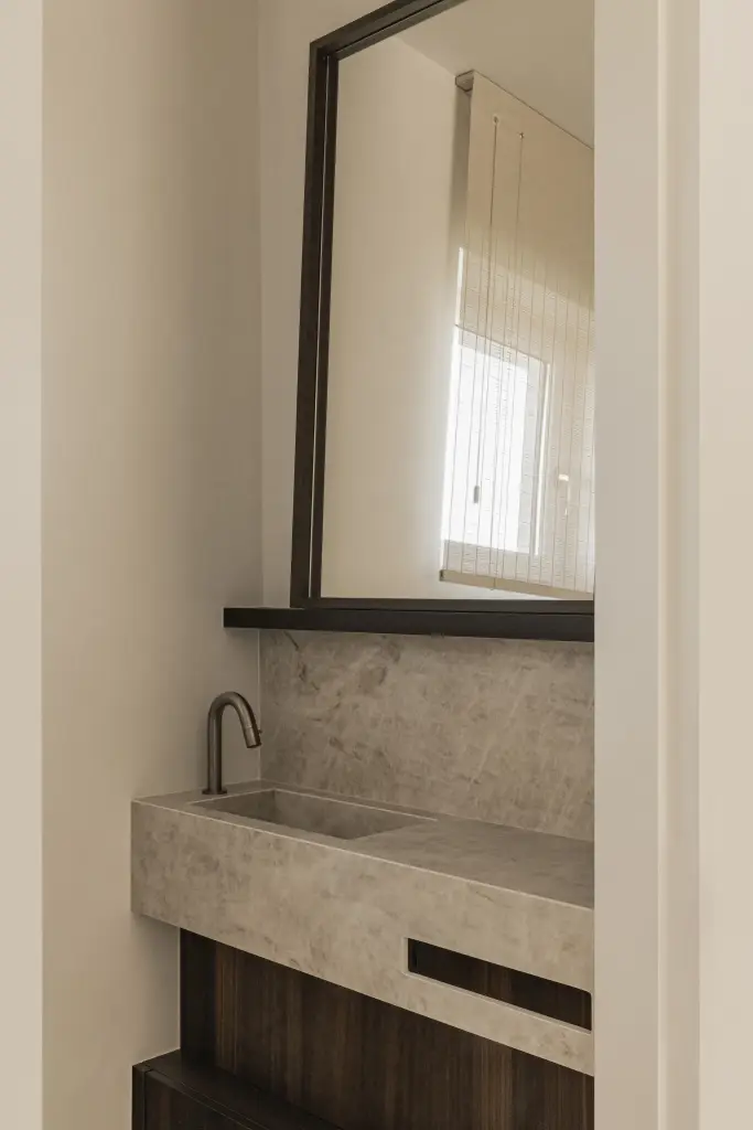 Wastafel in natuursteen met kraan en spiegel in donkere lijst, Villa in Loppem, interieur Laura Calleeuw