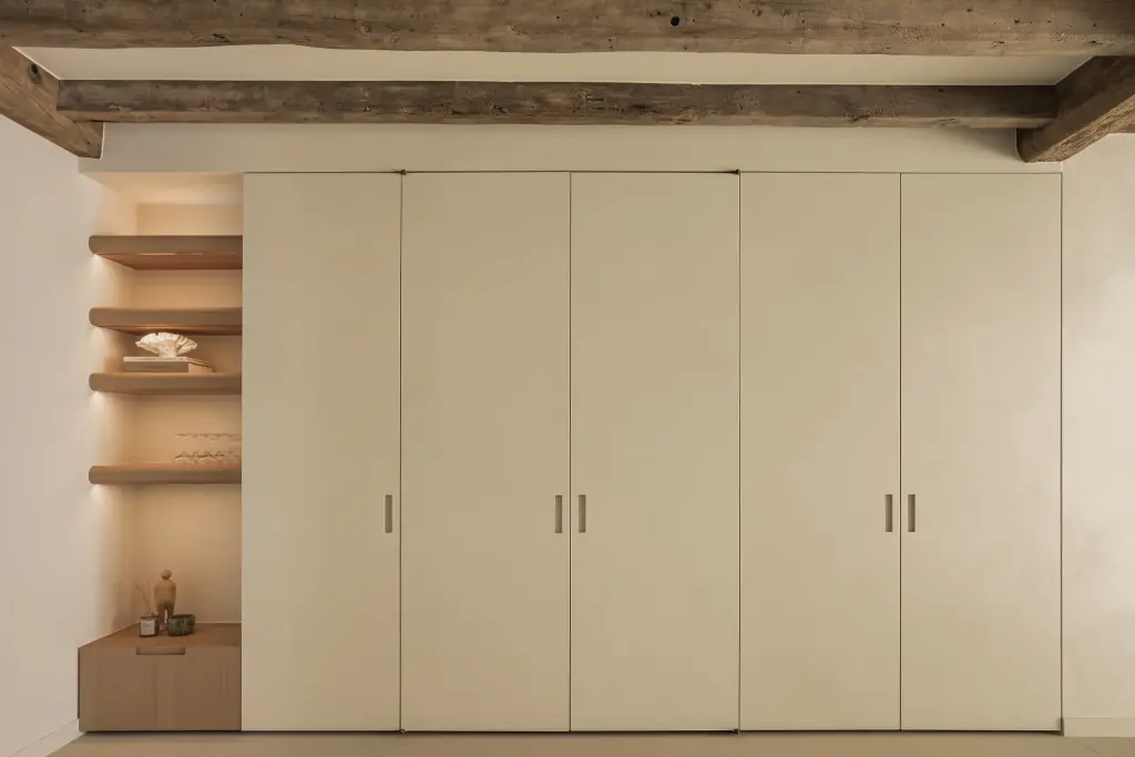 Gesloten kastenwand met crème deuren onder een eikenhouten balk, Totaalrenovatie in Loppem, interieur Laura Calleeuw